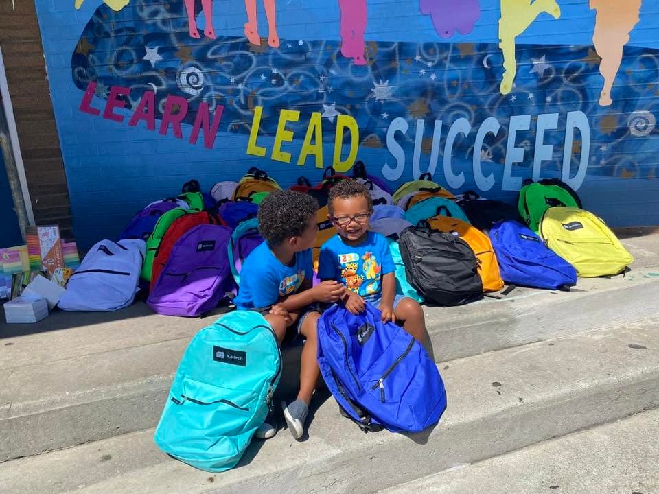 AnnMarie with Julius and Braydon surrounded by donated backpacks